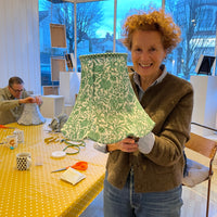 Person holding a green patterned traditional lampshade that they have made after my lampshade workshop brighton