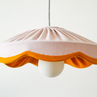 A dusty pink pleated scallop lampshade with a mustard linen edge, designed to fit a standard ceiling lamp.