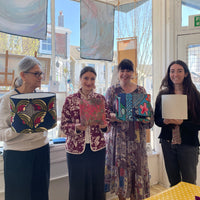 Four women holding colourful lampshades they made during a workshop