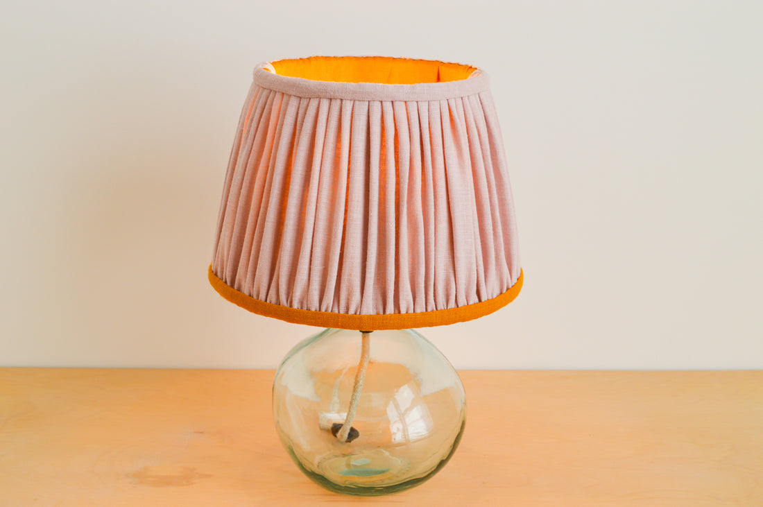 Hand gathered pink and mustard linen lampshade on a glass lamp base