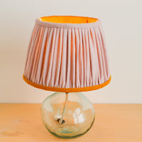 Hand gathered pink and mustard linen lampshade on a glass lamp base
