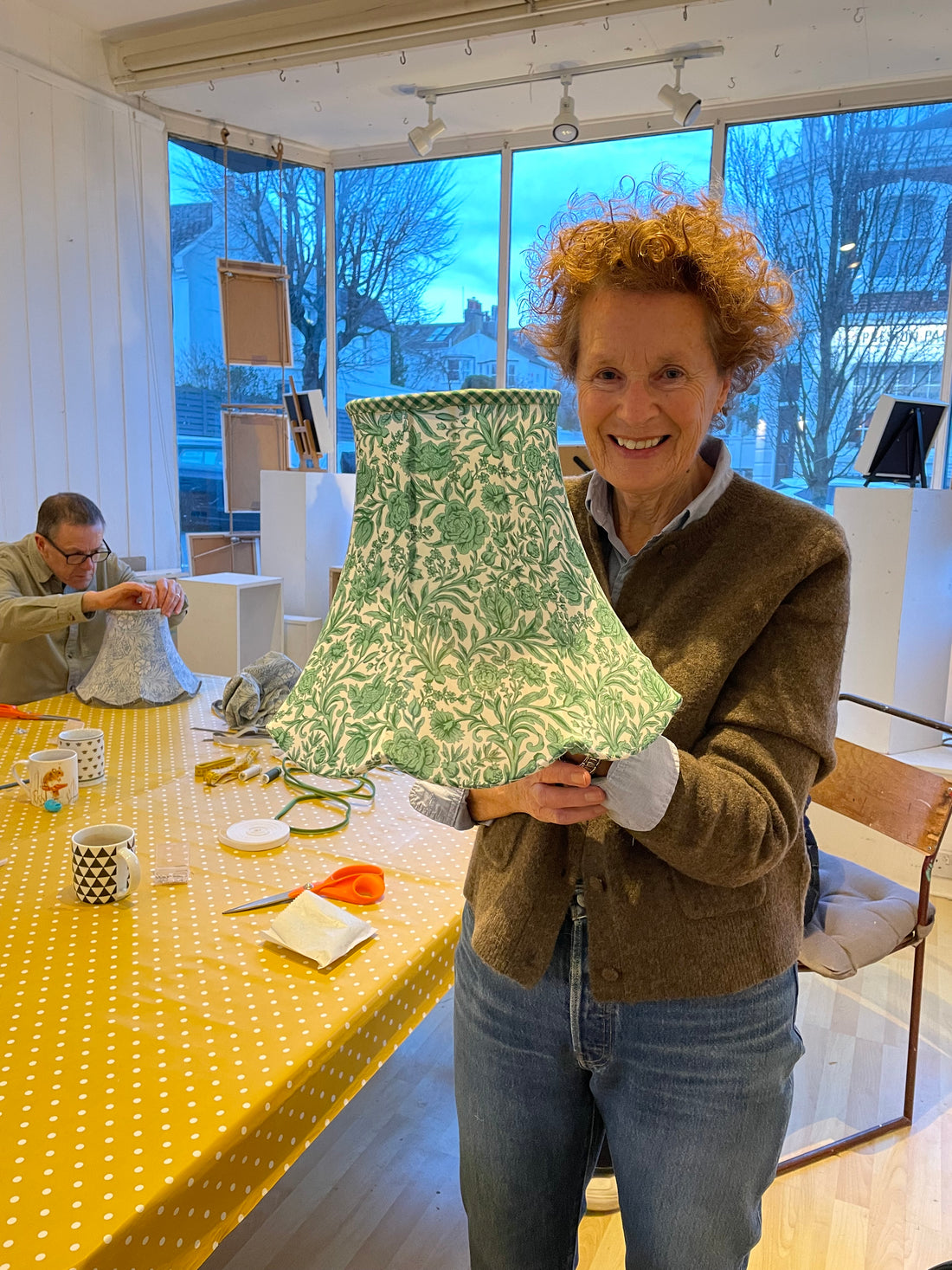 Person holding a green patterned traditional lampshade that they have made after my lampshade workshop brighton