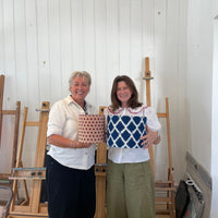 Two people holding the lampshades they have just made in the workshop