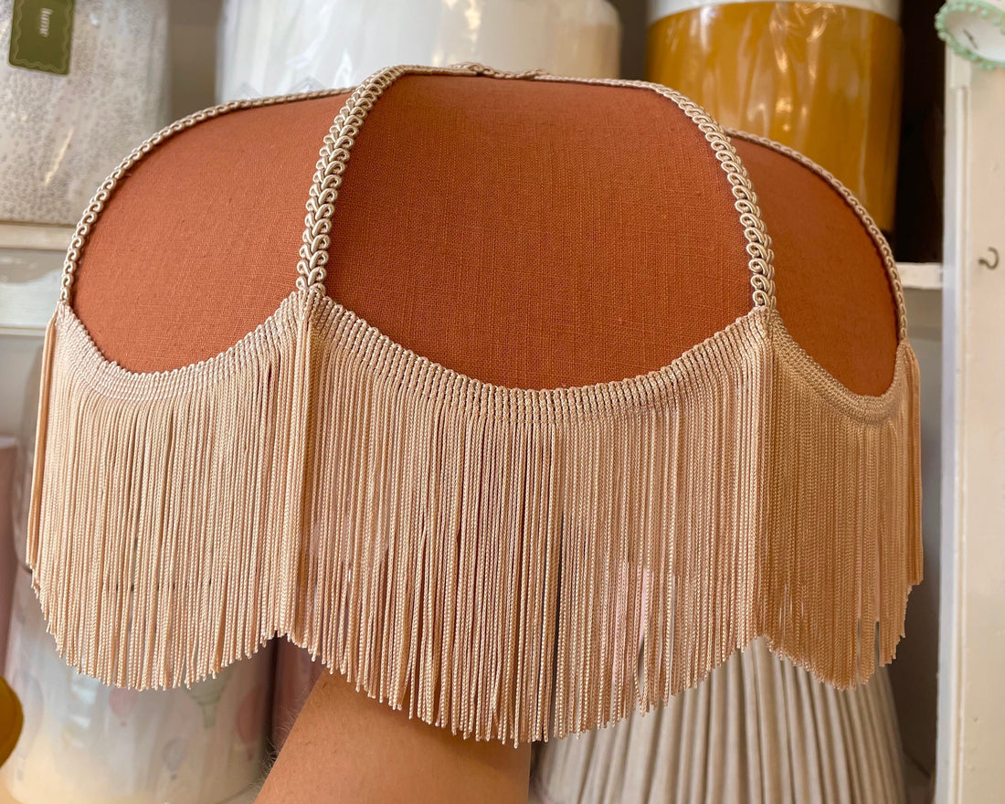 A close-up of a fringed rust coloured lampshade. Showing the vintage lampshade you can make in the workshop