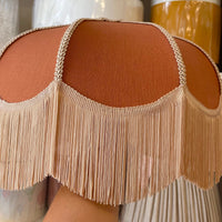A close-up of a fringed rust coloured lampshade. Showing the vintage lampshade you can make in the workshop