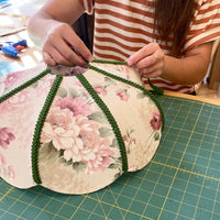 attaching braid to the vintage dome lampshade which they are making in the workshop